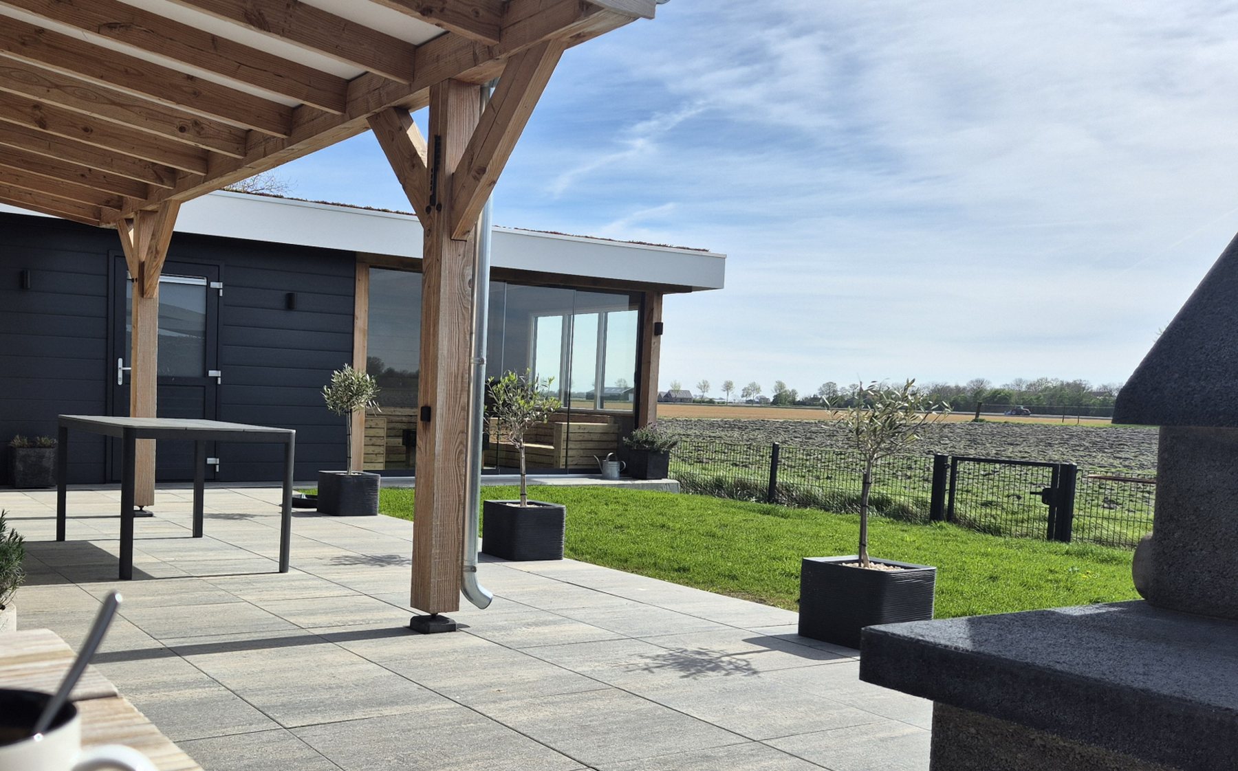 Het overkapte terras, met de tuin en de weilanden erachter